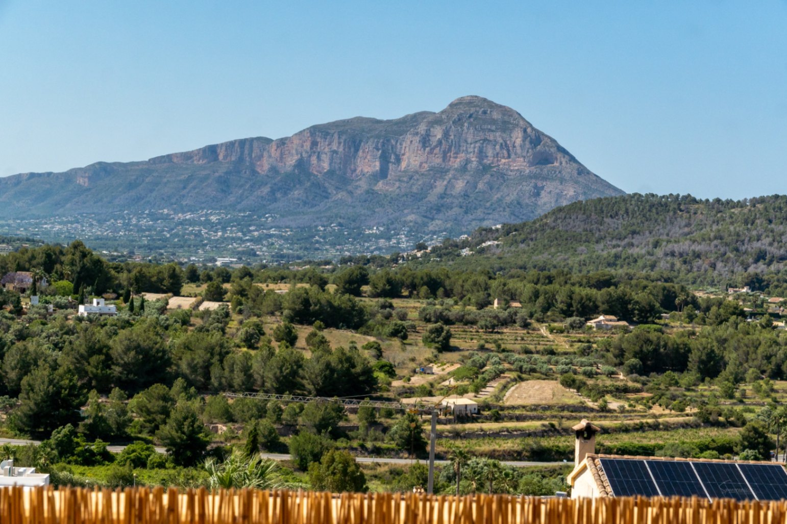 Panoramisch uitzicht op het Montgó-massief over een mediterrane vallei, met op de voorgrond een dak voorzien van fotovoltaïsche zonnepanelen.