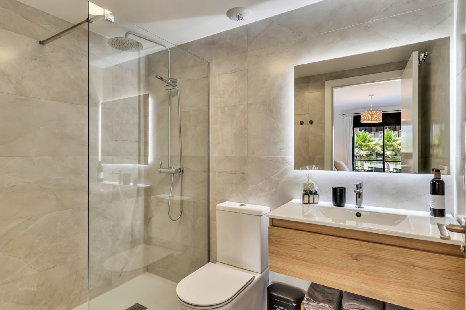 Moderne badkamer met inloopdouche, glazen wand en zwevend houten wastafelmeubel. Voorzien van een grote spiegel met LED-achtergrondverlichting en wandtegels met steeneffect.