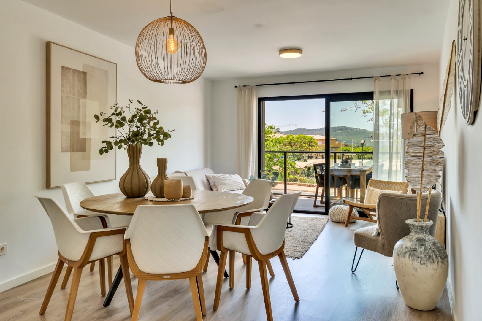 Open eetgedeelte met ronde houten tafel, designstoelen en directe toegang tot het terras met een panoramisch uitzicht op de bergen van Jávea.