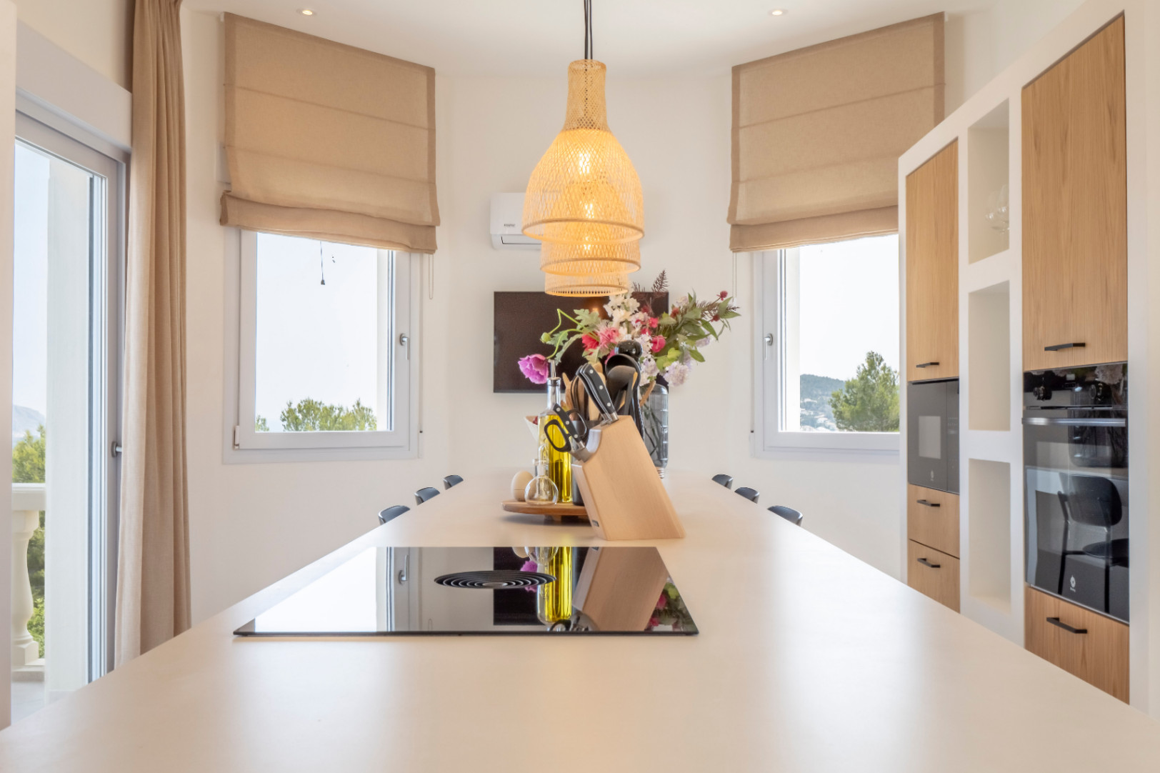 Keukendetail met centraal eiland, inductiekookplaat en hanglamp van wicker.