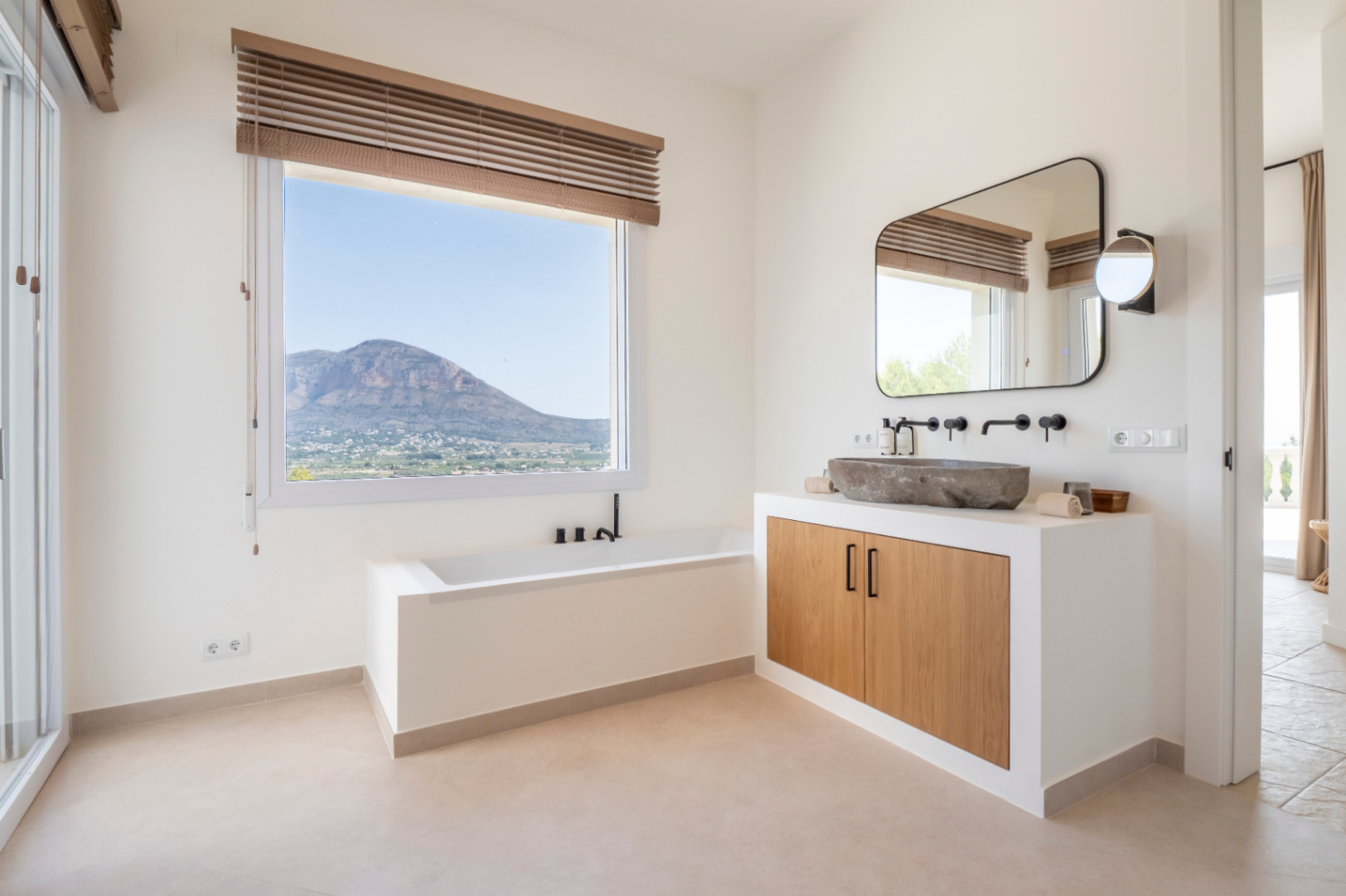 Lichte badkamer met stenen wastafel en uitzicht op de bergen. Modern, minimalistisch ontwerp.