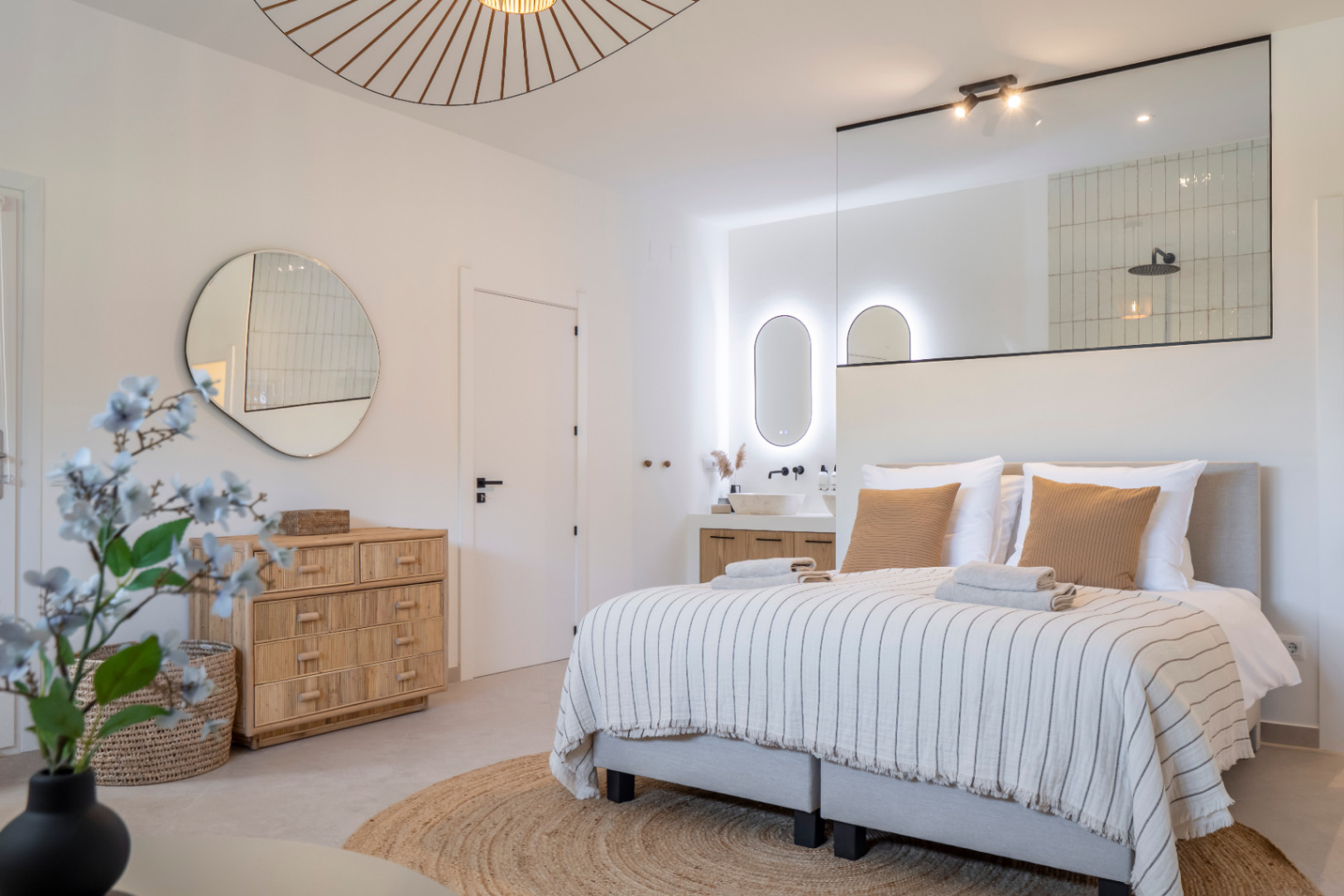 Lichte slaapkamer met geïntegreerde badkamer. Stenen wastafel en spiegel met achtergrondverlichting.