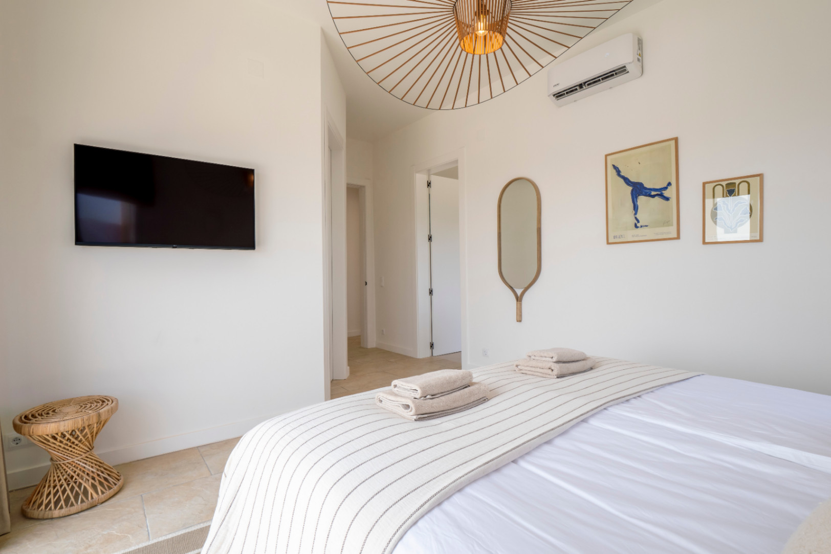 Lichte slaapkamer met tv, decoratieve spiegel en design plafondlamp.