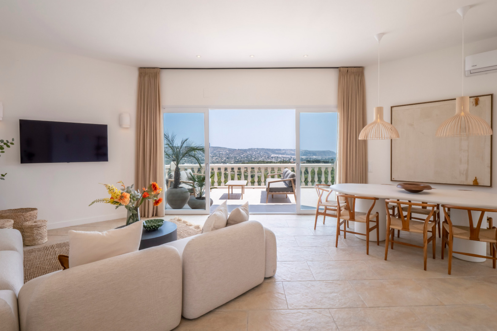 Lichte woon-eetkamer met toegang tot terras en panoramisch uitzicht. Modern design met lichte meubels en natuurlijke accenten.