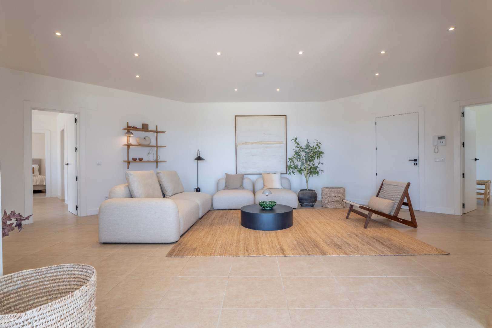 Lichte woonkamer met beige modulaire bank, jute vloerkleed en minimalistische inrichting. Inbouwverlichting.