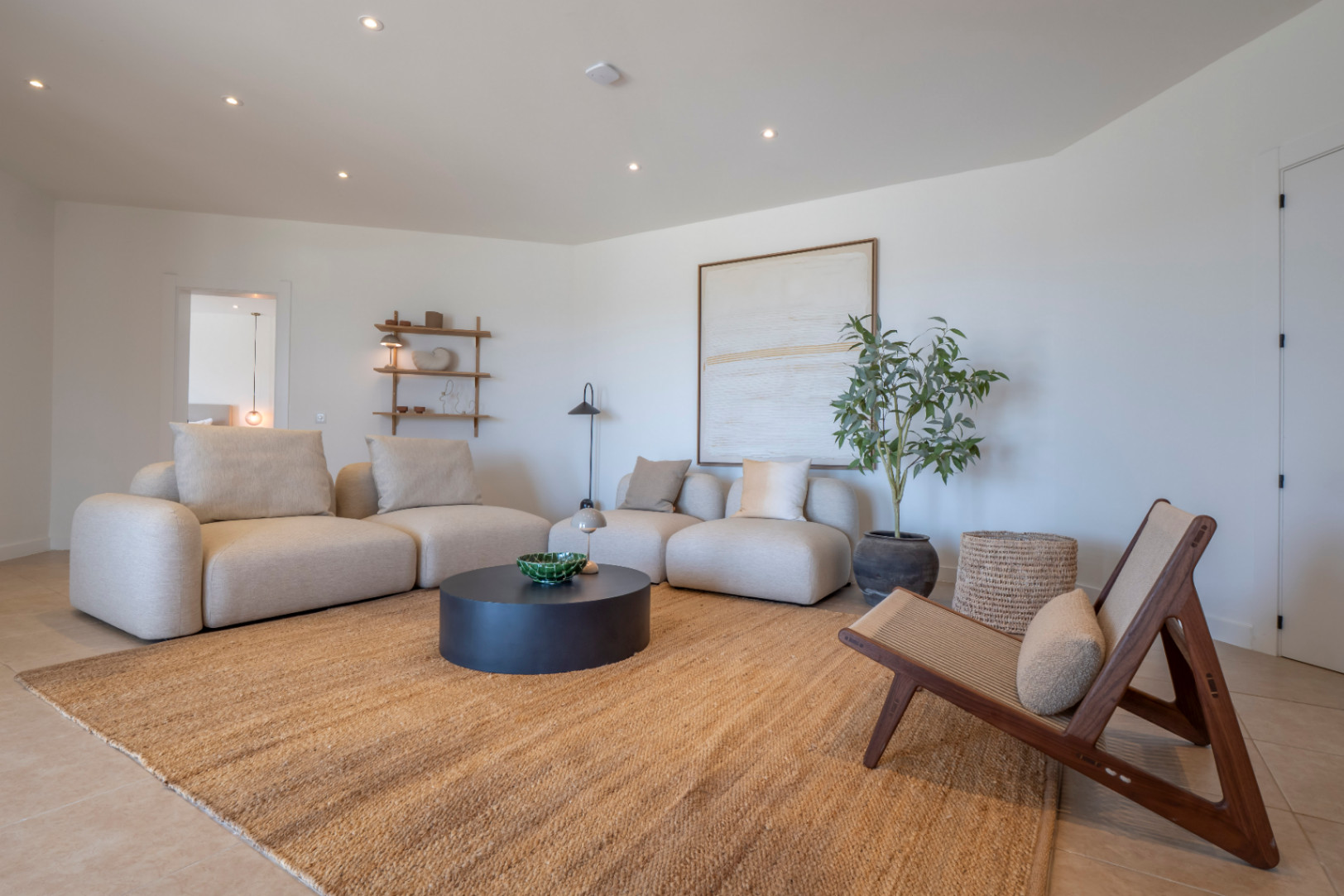 Lichte woonkamer met beige modulaire banken, jute vloerkleed en minimalistische decoratieve details.