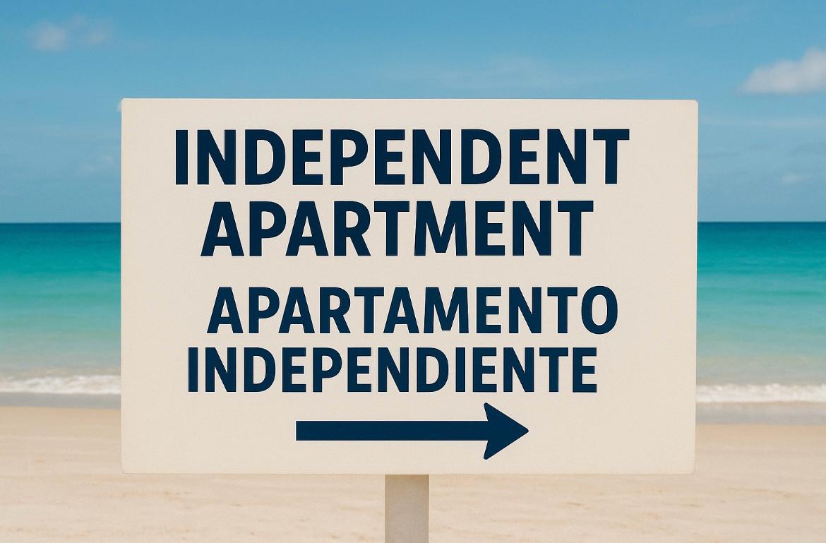 Tweetalig bord op het strand dat de richting aangeeft van onafhankelijke appartementen.