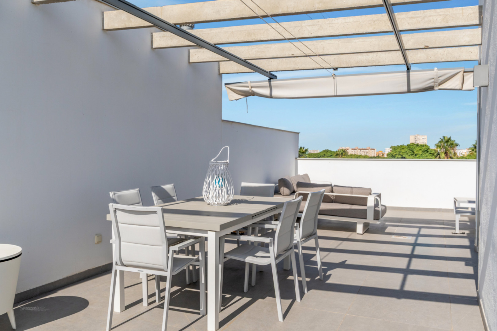 Privé dakterras met betonnen pergola, uitschuifbaar zonnescherm en een eethoek buiten met vrij uitzicht over de omgeving.