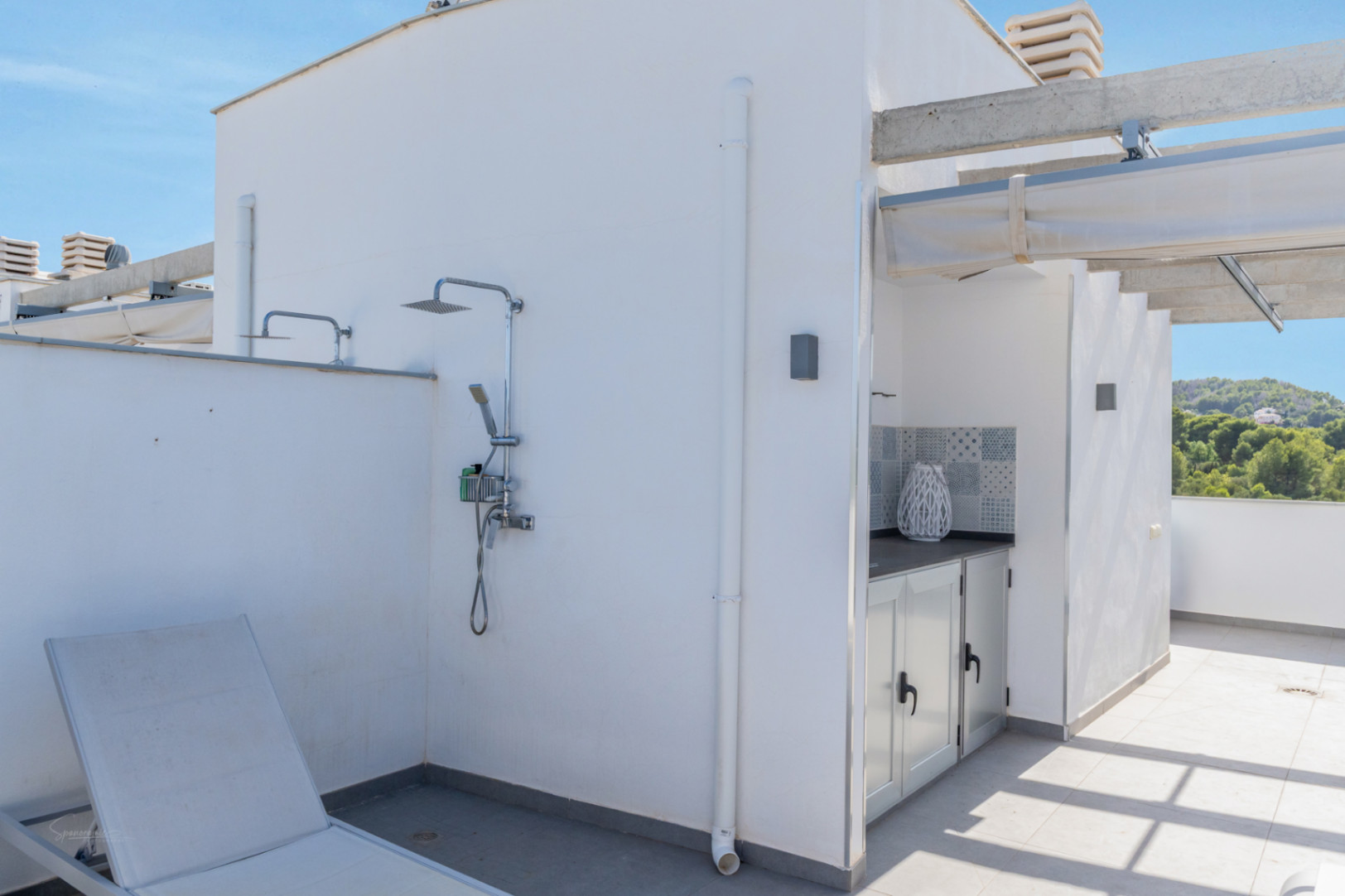 Privé dakterras met chromen buitendouche, een zomerkeuken met decoratieve tegels en een pergola voorzien van een uitschuifbaar zonnescherm.