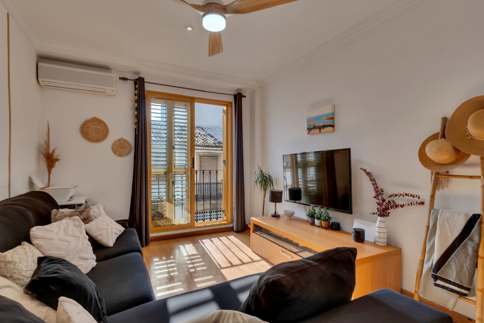 Lichte woonkamer met houten vloer, airconditioning en balkon met traditionele houten luiken en uitzicht op de historische kern van Jávea.