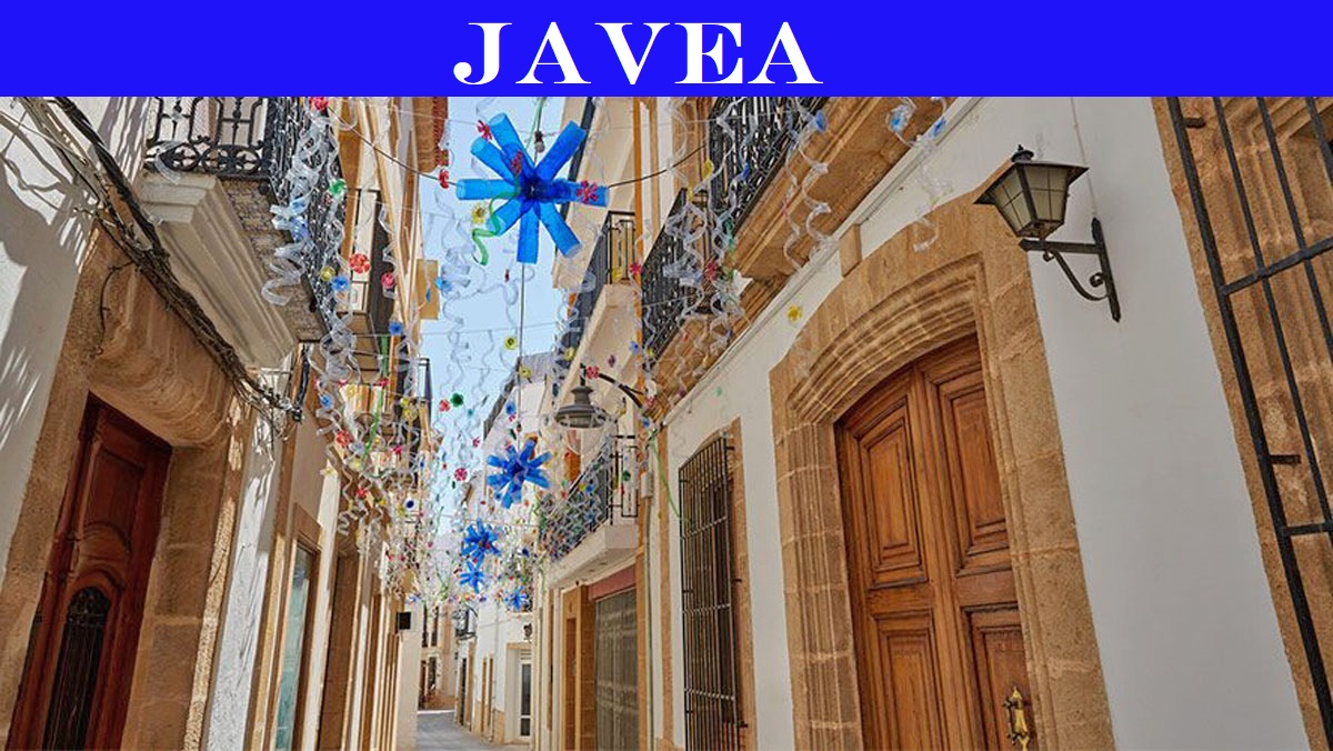 Traditionele straat in het historische centrum van Jávea met Tosca stenen deuromlijstingen, smeedijzeren balkons en feestelijke versieringen tussen de gebouwen.