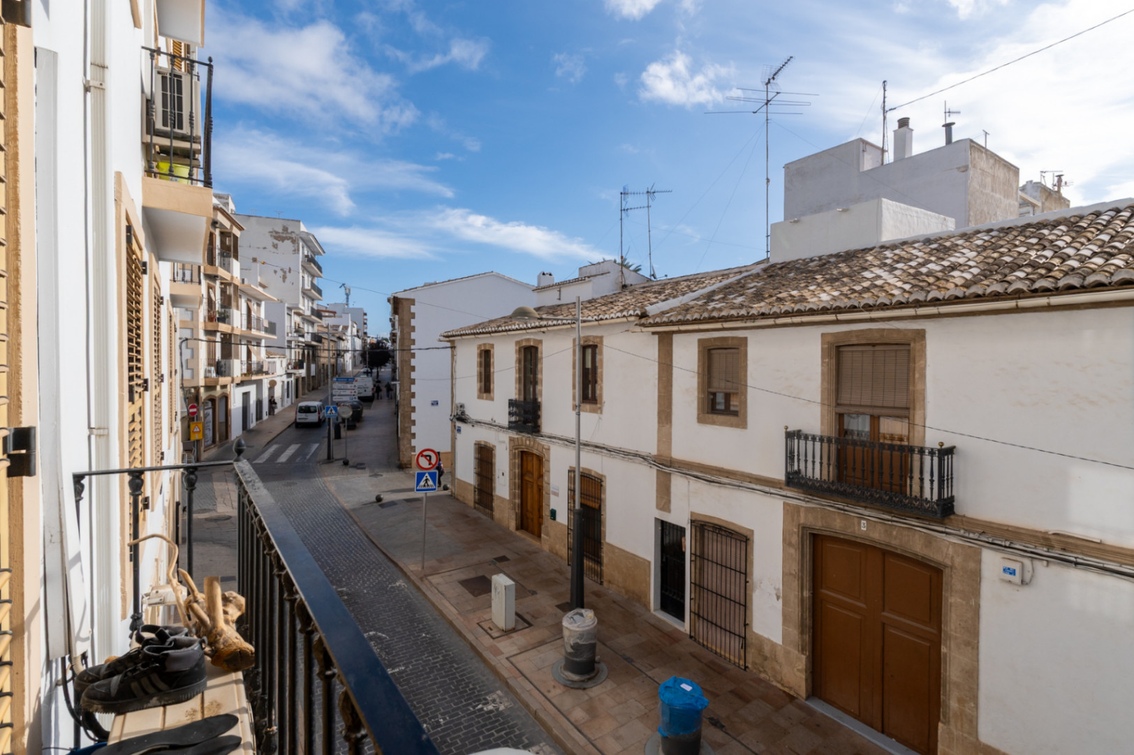 Uitzicht vanaf het balkon op een straat in het historische centrum van Jávea, met traditionele witte gevels, pannendaken en natuurstenen architectonische details.
