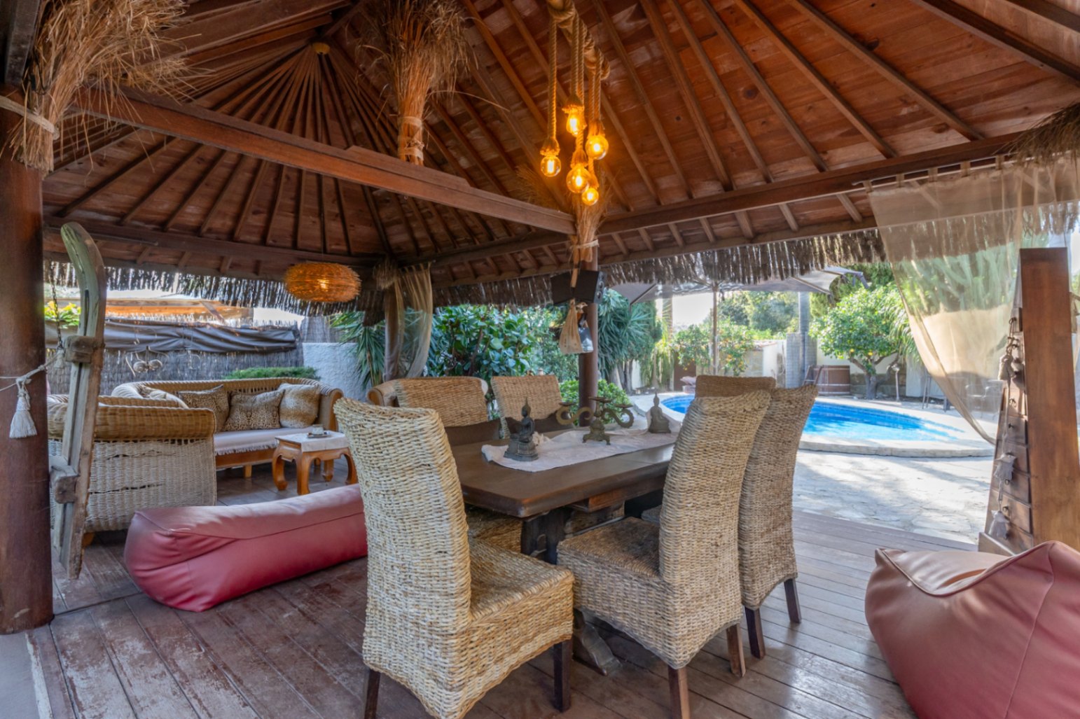 Houten pergola in Balinese stijl met houten terras, rieten meubilair en direct uitzicht op het privézwembad.