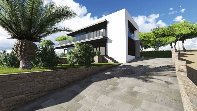 Exterieur van de moderne villa met een oprit van natuursteen, stenen muren, witte gevel met glazen balkons en mediterrane beplanting.