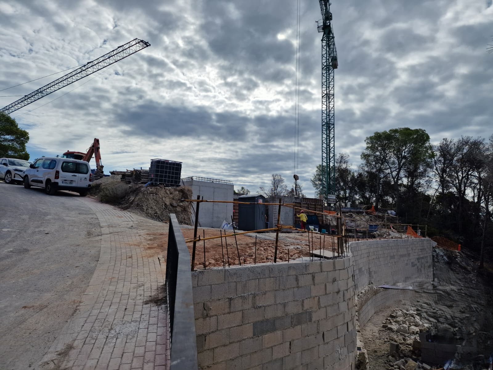 Huidige bouwstatus in Moraira, met de gebogen steunmuren, de geplaveide toegangsweg en zware machines tijdens de eerste structurele fase van de villa.