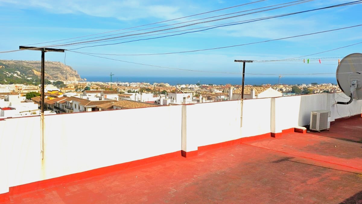 Gemeenschappelijk dakterras met rode vloertegels en weids uitzicht over de oude stad van Javea en de Middellandse Zee.