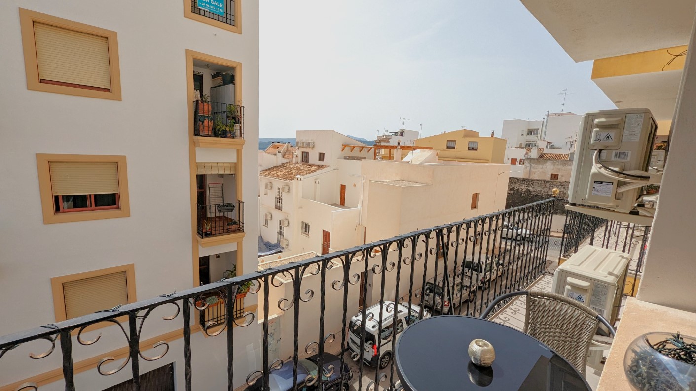 Privébalkon met smeedijzeren balustrade, voorzien van een bistroset en uitzicht op de karakteristieke witte architectuur van de oude binnenstad van Javea.
