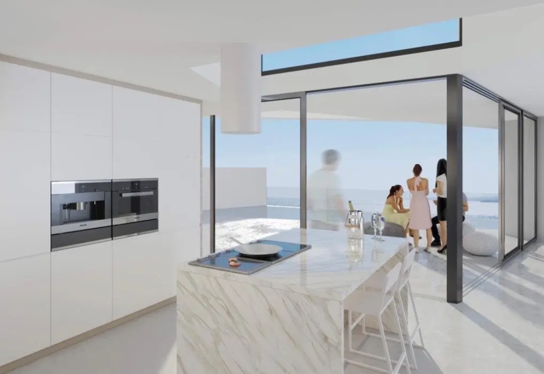 Moderne keuken met marmeren kookeiland, minimalistische witte kasten en kamerhoge glazen schuifdeuren naar het terras met uitzicht op zee.