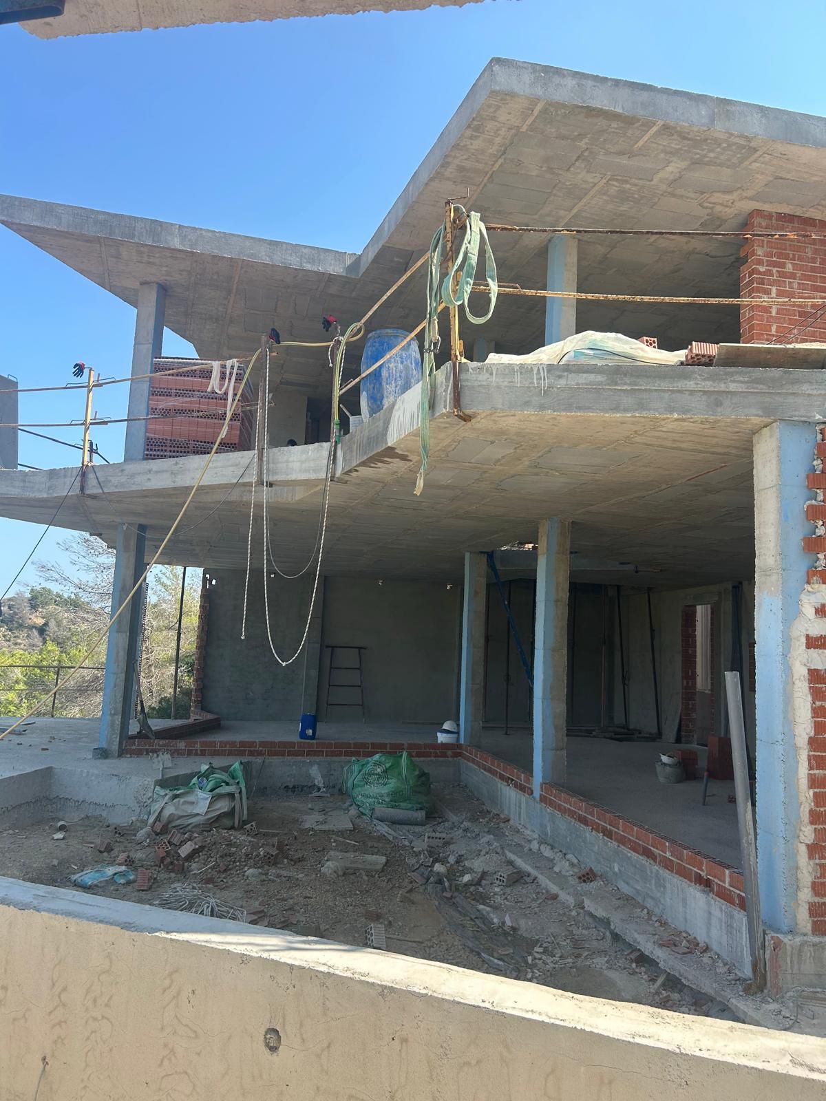 Ruwbouwfase van een villa met meerdere verdiepingen in Benitachell, met gewapend betonnen vloeren, kolommen en eerste metselwerk.
