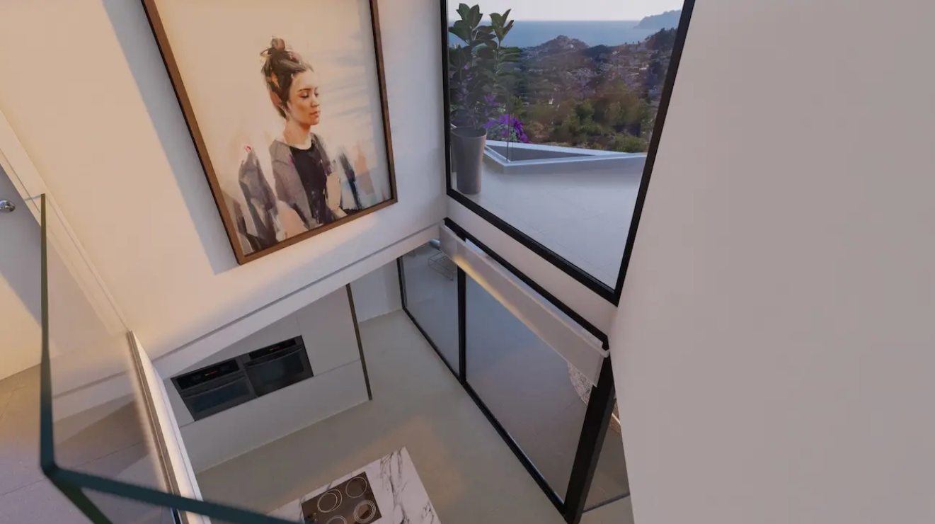 Uitzicht vanaf de bovenverdieping op de dubbelhoge keuken met marmeren kookeiland, grote raampartijen met zeezicht en een glazen balustrade.