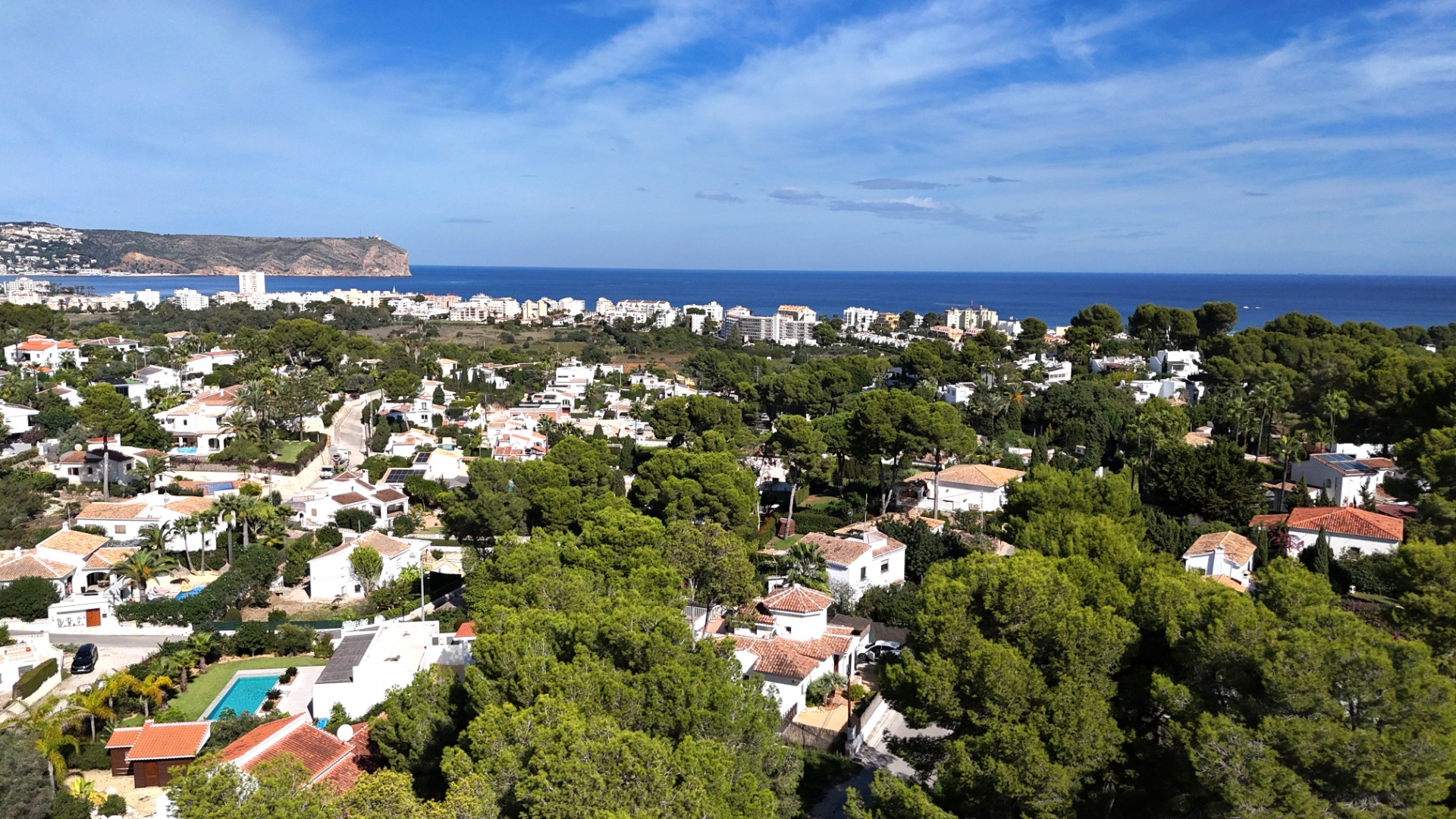 Verhoogd panoramisch uitzicht over de woonwijk Toscal in Jávea, met mediterrane villa's tussen de pijnbomen en Cabo de San Antonio aan de horizon.