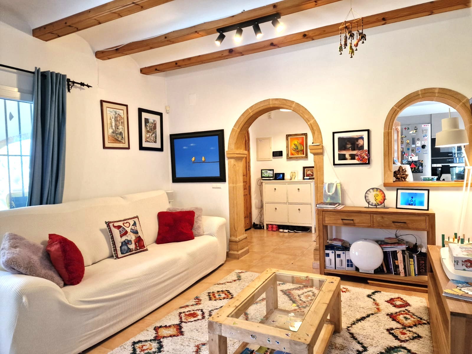 Woonkamer met traditionele houten balkenplafonds, Tosca stenen bogen en een lichte indeling die via een boogopening verbonden is met de keuken.