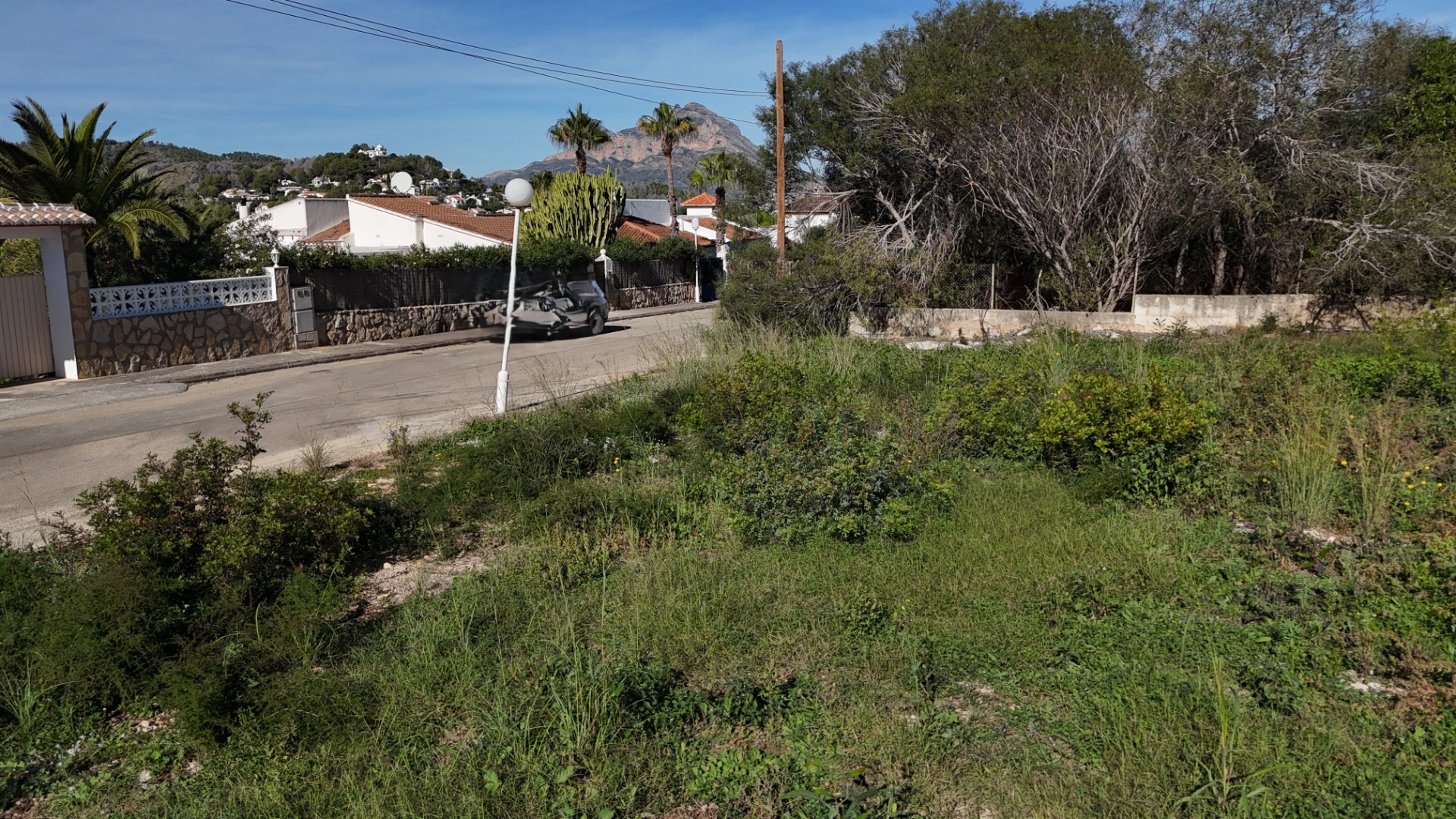 Vlak bouwperceel in Pinosol, Jávea, met directe toegang tot de weg en vrij uitzicht op de Montgó in een rustige woonwijk.