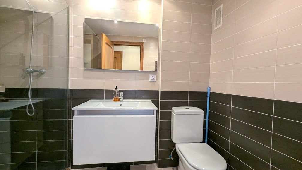 Moderne badkamer met tweekleurige wandtegels, wit zwevend wastafelmeubel, rechthoekige spiegel en inloopdouche met glazen wand.