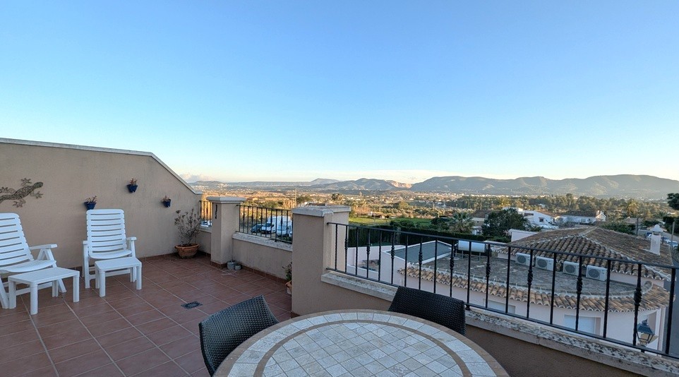 Ruim dakterras met terracotta tegels, eethoek buiten en een panoramisch vrij uitzicht over het omliggende landschap en de bergen.