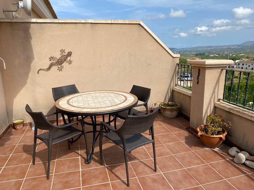 Terras met terracotta tegels, een mozaïektafel met vier stoelen en vrij uitzicht over het omliggende landschap en de bergen.