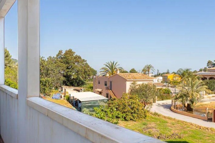 Uitzicht vanaf het balkon op het dorp Jesús Pobre, met mediterrane architectuur, palmbomen en een weids panorama over het omliggende platteland.