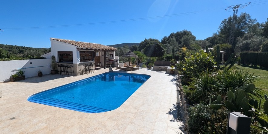 Buitenzwembad met natuurstenen terras, een ingerichte buitenkeuken met bar en een mediterrane tuin met vrij uitzicht op het omliggende landschap.