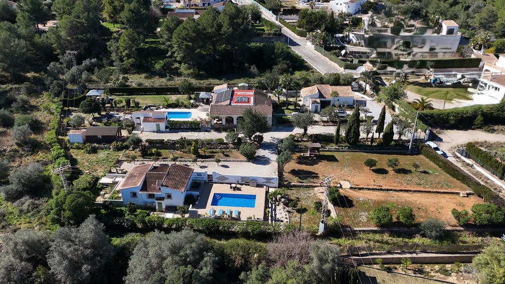 Luchtfoto van het perceel van 4.600 m² met twee onafhankelijke villa's met privézwembaden, een houten chalet en het hoofdhuis voorzien van zonnepanelen en een glazen koepel.