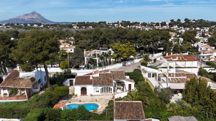 Luchtfoto van de traditionele villa met privézwembad, terracotta daken en volgroeide tuin, met de berg Montgó op de achtergrond.