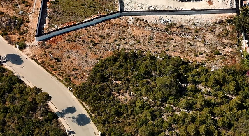 Luchtfoto van het perceel van 1.528 m² in Lomas del Rey, met het uitgegraven terrein, de omheiningsmuur en directe toegang vanaf de geasfalteerde weg.