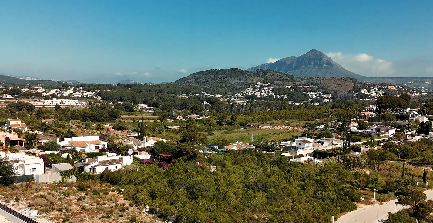 Verhoogd uitzicht over de urbanisatie Lomas del Rey in Jávea, met de iconische Montgó-berg op de achtergrond en omliggende mediterrane villa's en groen.