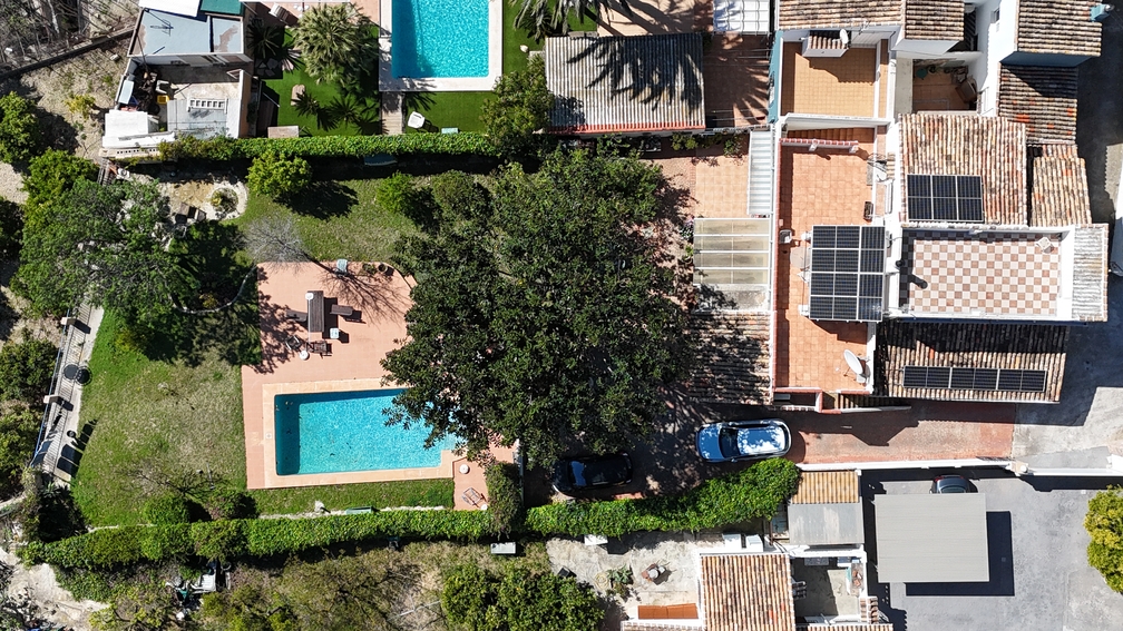 Luchtfoto van de villa met privézwembad, tuin en zonnepanelen op het pannendak, omgeven door weelderig mediterraan groen.