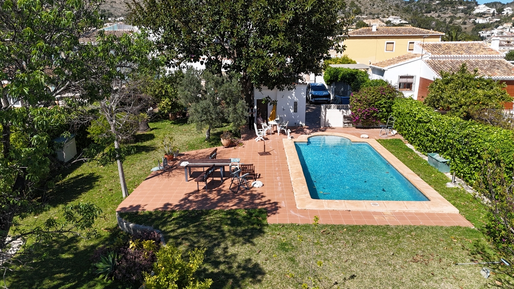 Privézwembad met een terracotta terras en gazon. Volgroeide bomen en hagen bieden privacy voor de eethoek buiten en de mediterrane tuin.