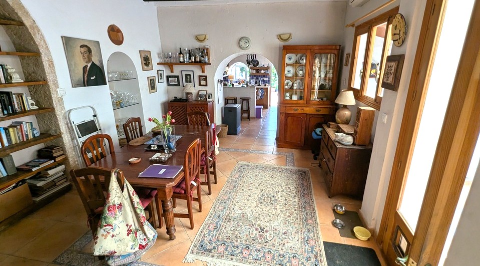 Ruime eetkamer met traditionele terracotta tegels, een houten tafel en authentieke Tosca stenen bogen met ingebouwde schappen en doorgang naar de keuken.