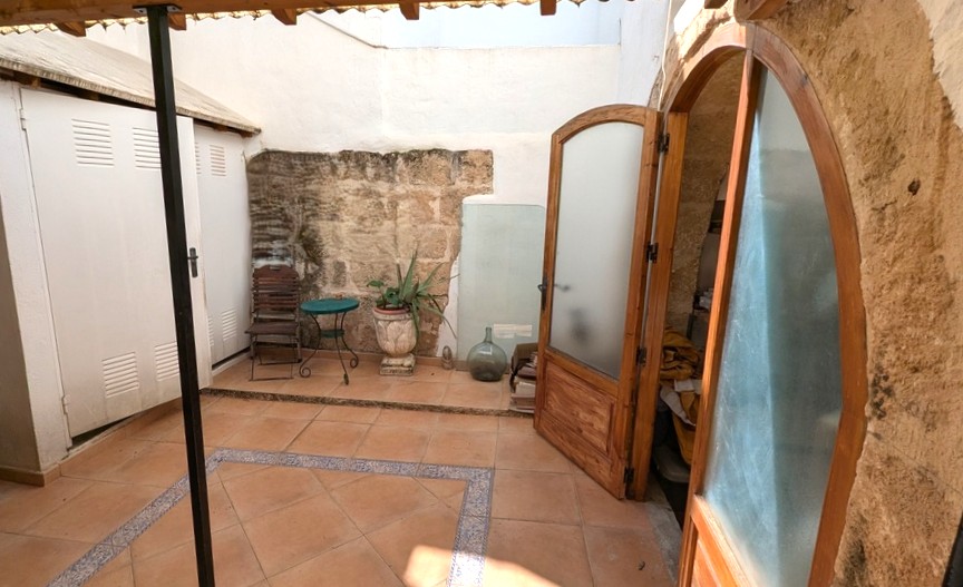 Traditionele patio met authentieke Tosca-natuurstenen muren, terracotta vloertegels met sierranden en houten boogdeuren naar de binnenruimtes.