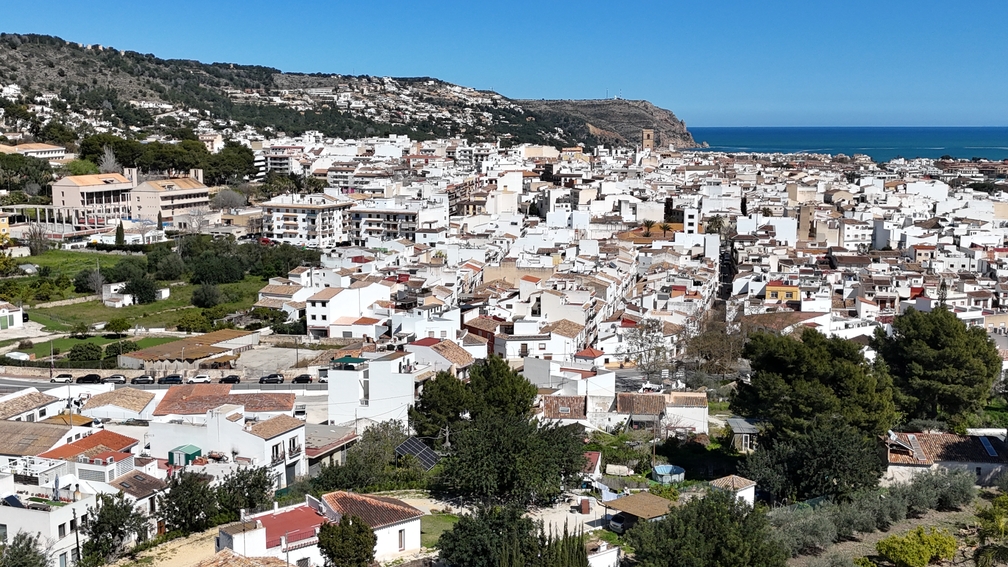 Verhoogd panoramisch uitzicht op het historische centrum van Javea, met de traditionele witte bebouwing, de kerktoren van San Bartolomé en de Middellandse Zee.