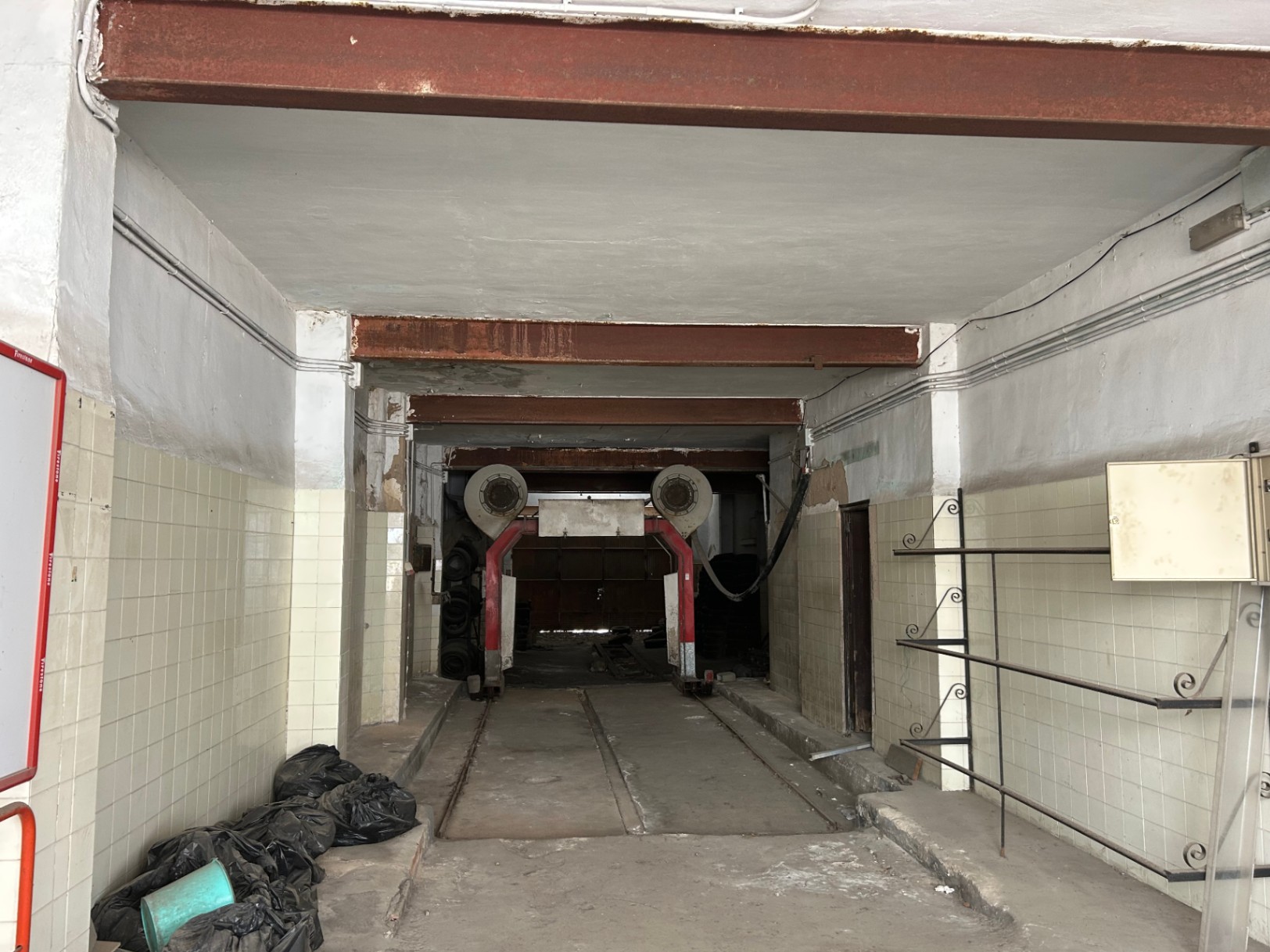 Commerciële ruimte van 175 m² op de begane grond met hoge plafonds, zichtbare stalen balken en industriële rails, ideaal voor herontwikkeling tot loft of garage.