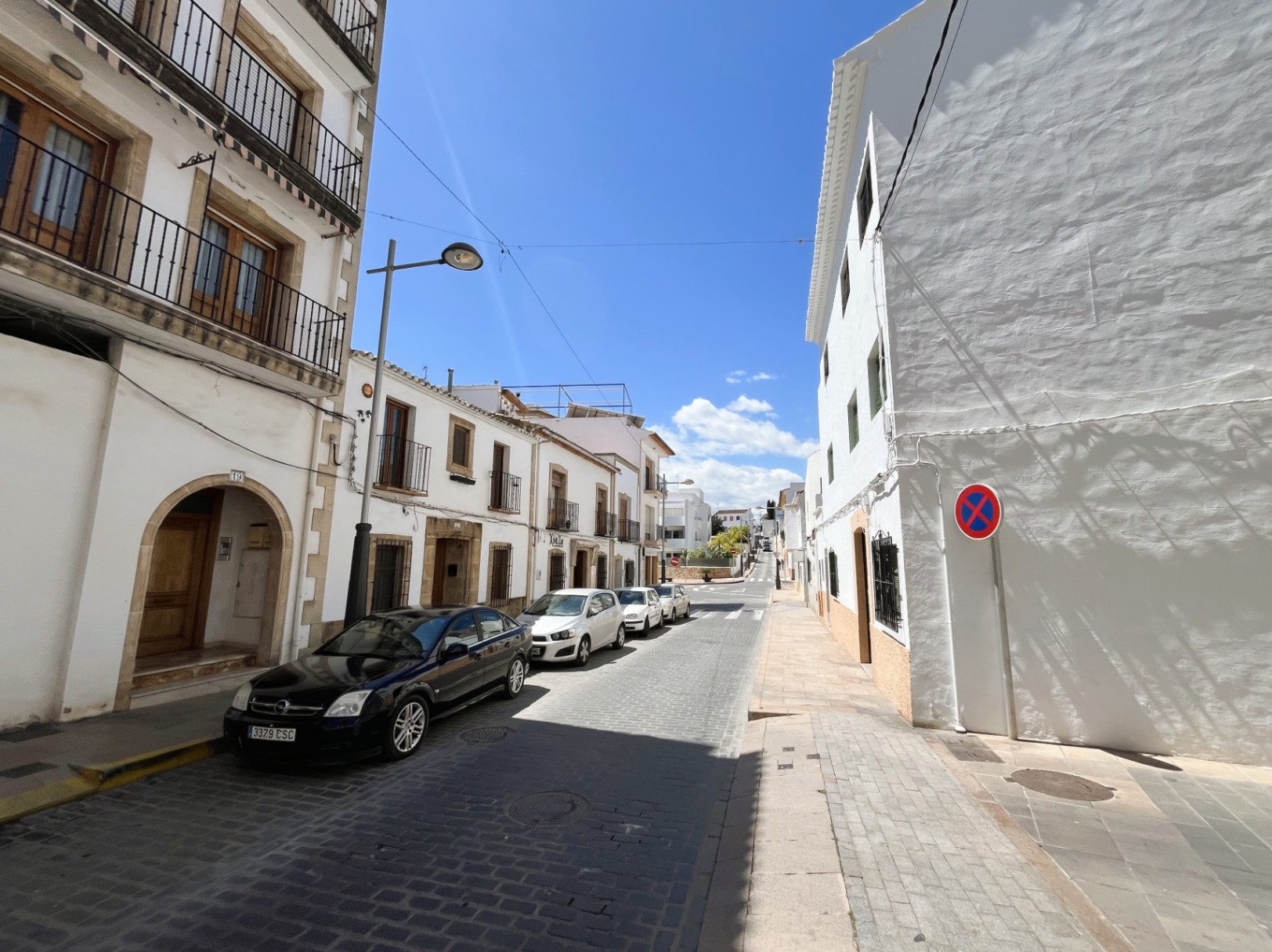 Externe gevel van het gebouw in een geplaveide straat in het oude centrum van Jávea, met traditionele Tosca stenen bogen en smeedijzeren balkons.
