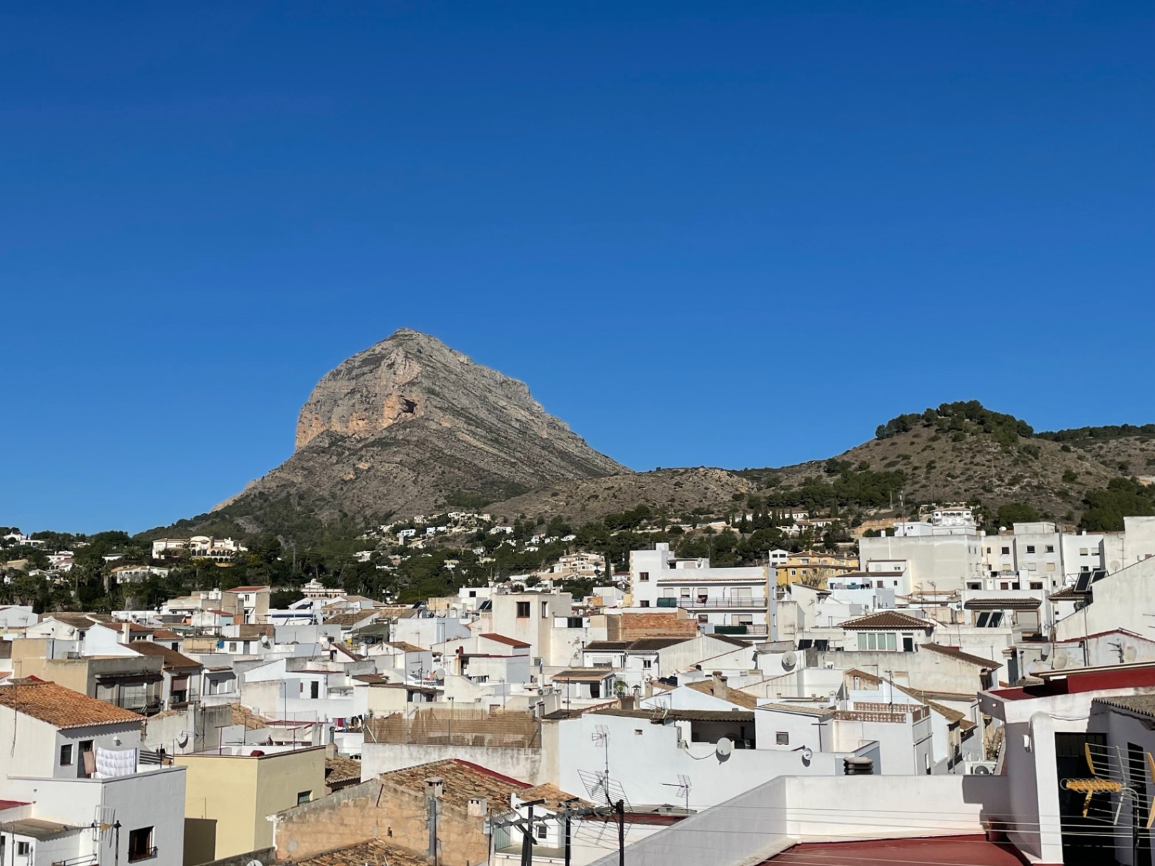 Panoramisch uitzicht vanaf het dakterras op de Montgó-berg en het historische centrum van Jávea, met traditionele witte gevels en pannendaken.