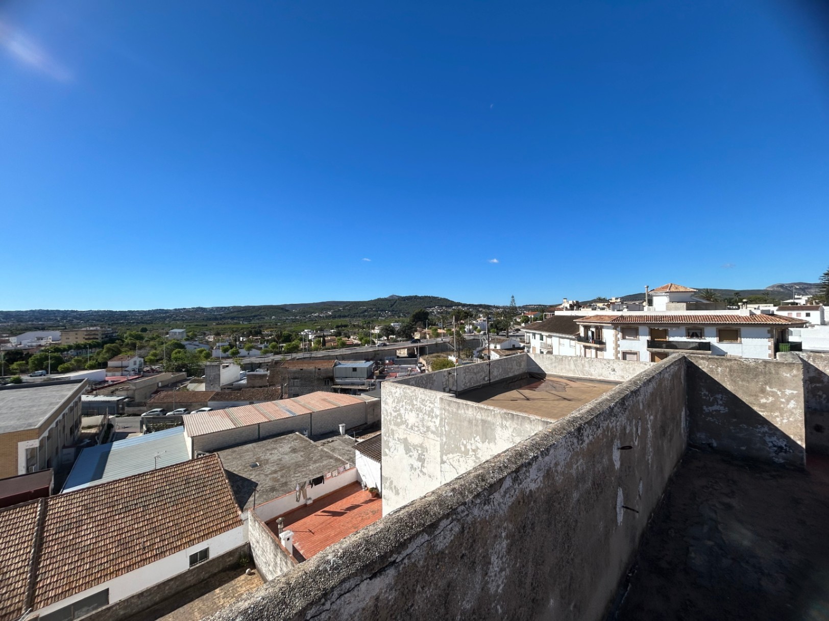 Verhoogd perspectief vanaf het gemeenschappelijke dakterras met panoramisch uitzicht op het stadsbeeld van Jávea en de bergen.