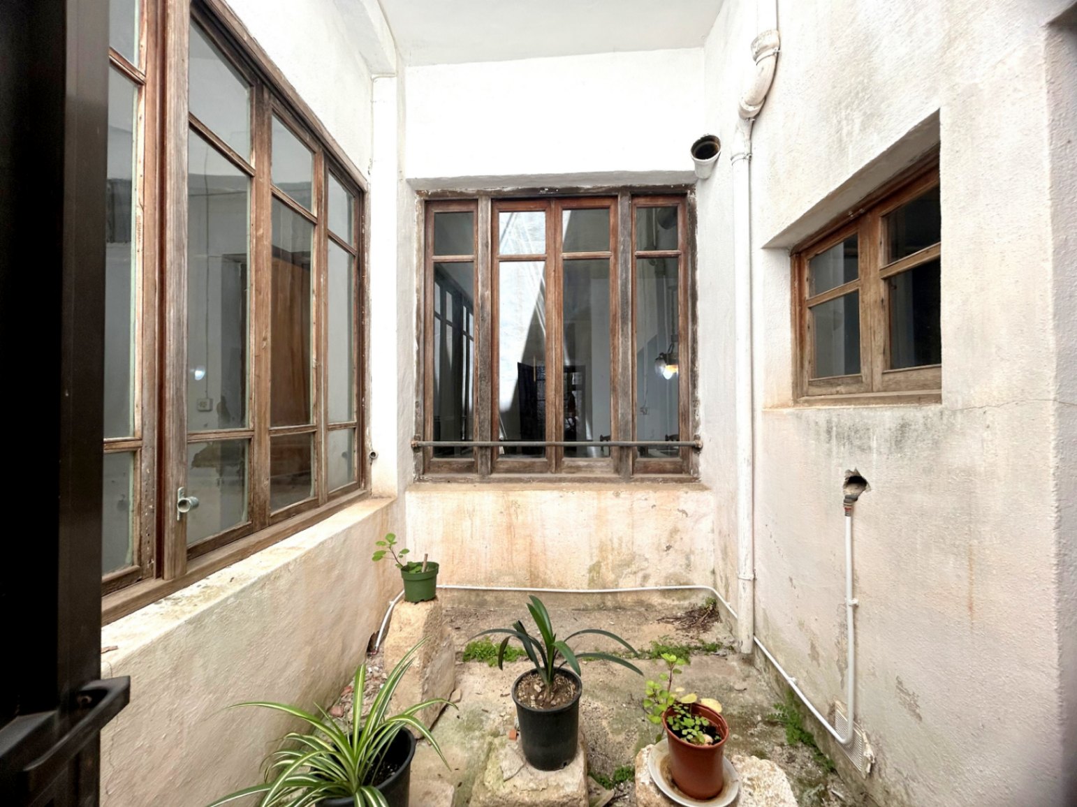 Centrale lichtschacht met originele grote houten raamkozijnen en witgekalkte muren, die zorgt voor natuurlijk licht en ventilatie in de historische woning.