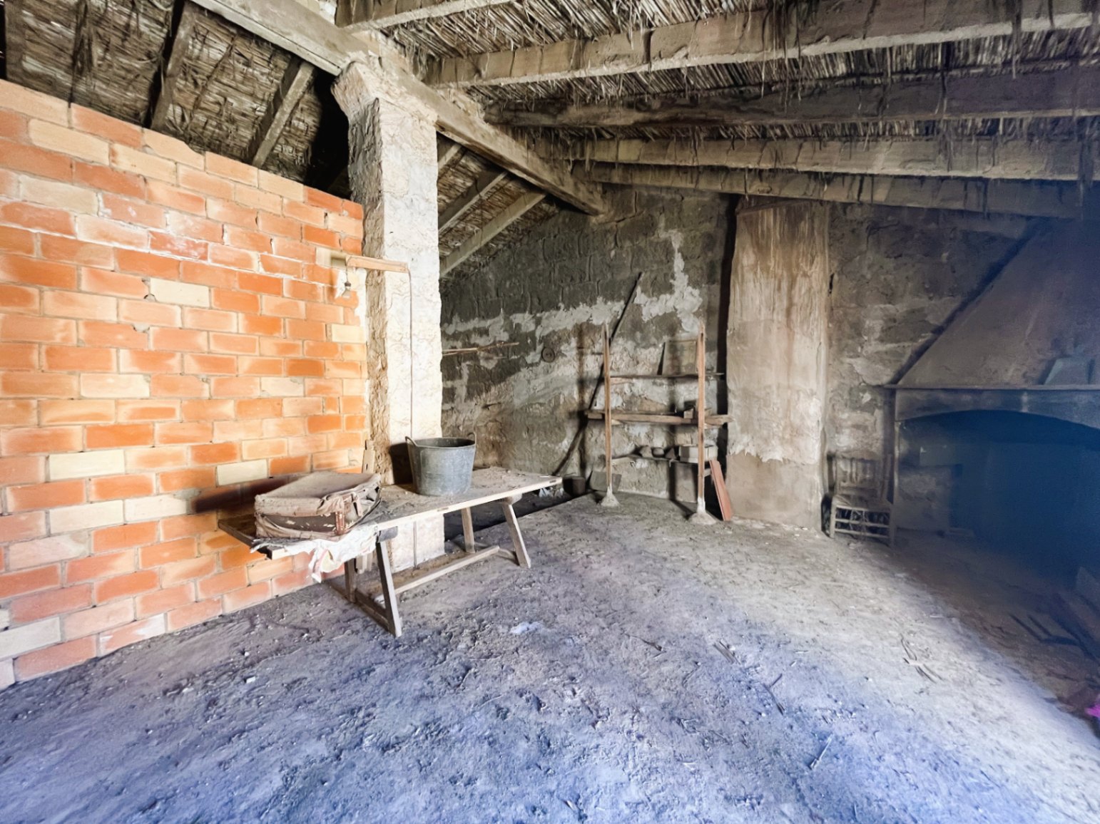 Open zolder met originele rieten plafonds en houten balken. Rustieke ruimte met een stenen open haard en veel mogelijkheden voor volledige renovatie.
