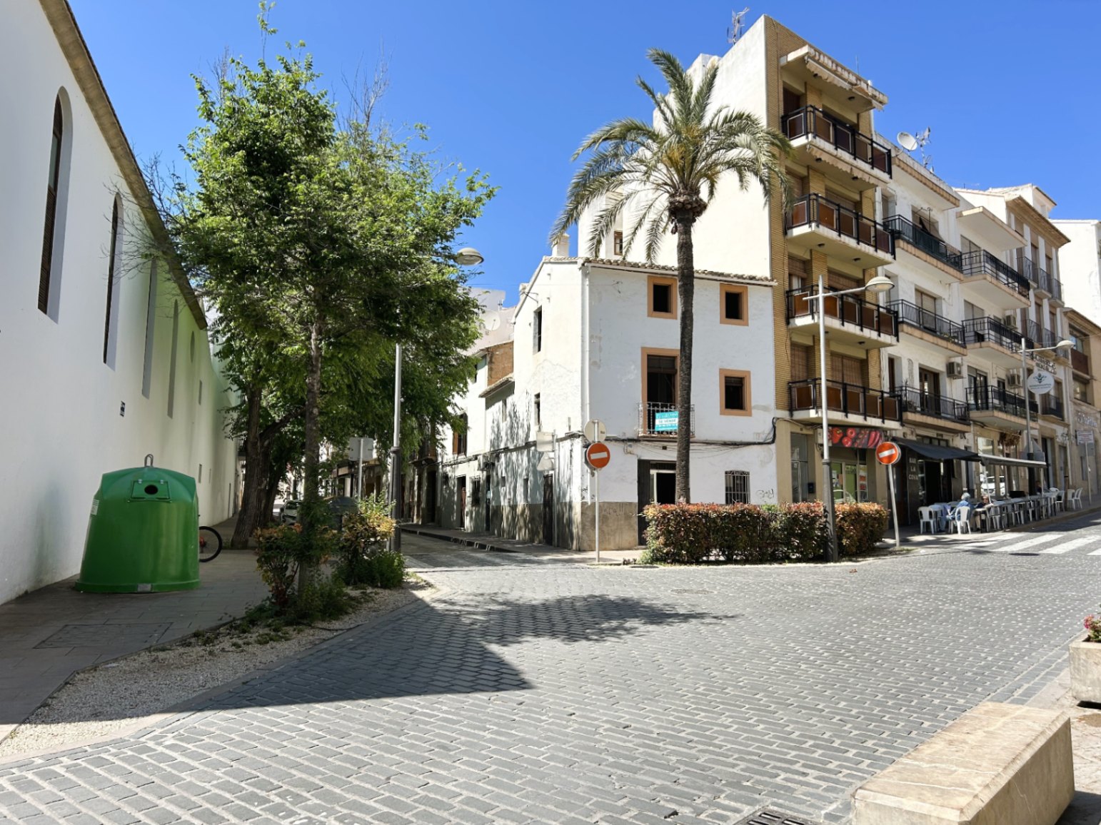 Buitenaanzicht van de witte hoekgevel in een geplaveide straat in het historische centrum van Jávea, met een palmboom en traditionele architectuur.