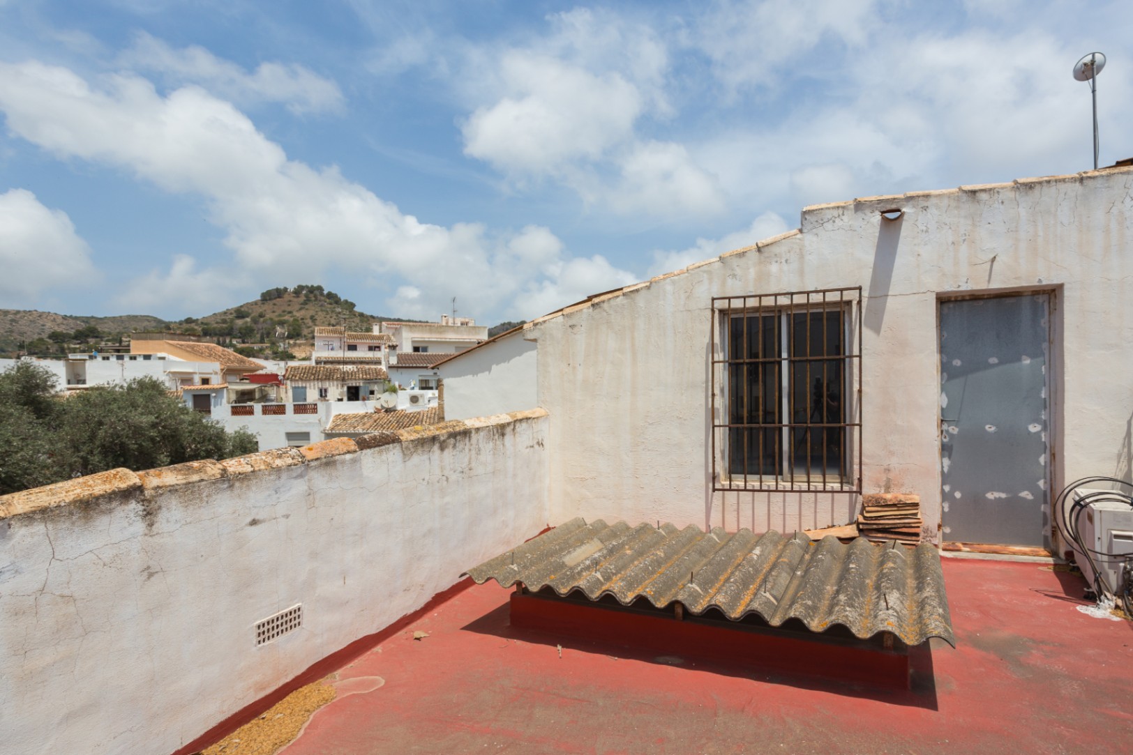 Dakterras met een rood geschilderde vloer en weids uitzicht over de stad en de omliggende heuvels van Jávea. Voorzien van directe toegang.