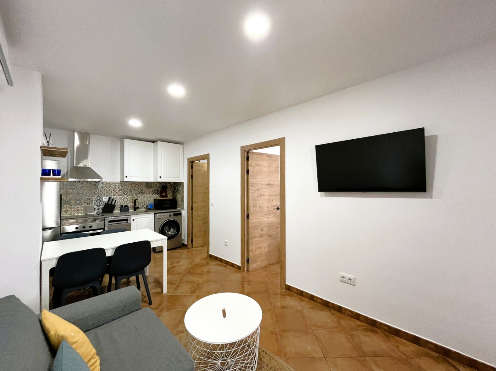 Open woonruimte met een moderne keuken voorzien van patroontegels, inbouwspots en een diagonale tegelvloer in warme kleurstelling.